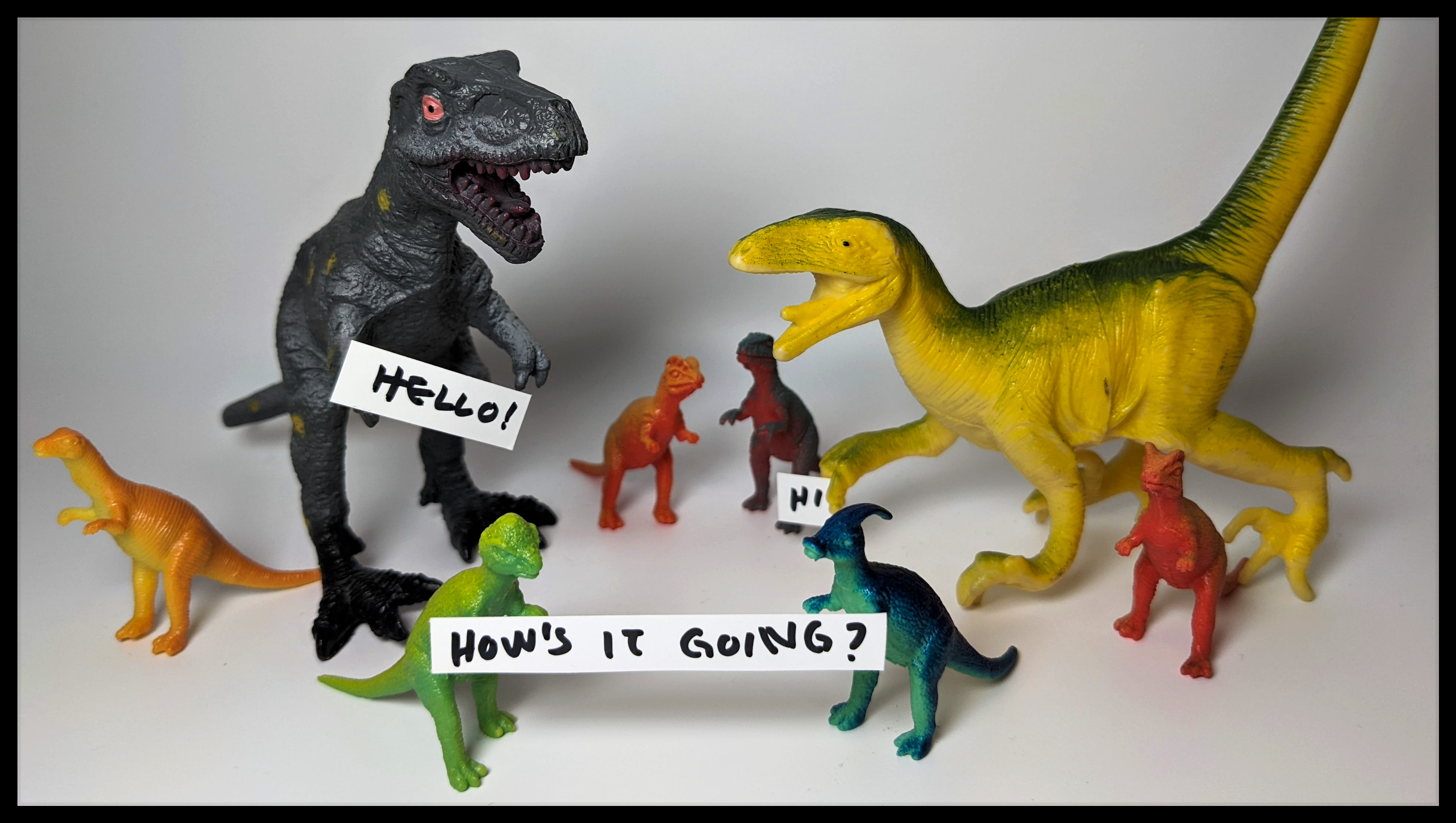 Toy dinosaurs holding signs: "Hello," "Hi," and "How's it going?" 